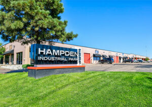 Hampden Business Park sign and building, green lawn and evergreen tree